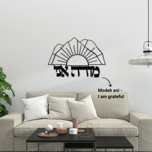 Hebrew metal sign “Modeh Ani” alongside a sunrise over the mountains